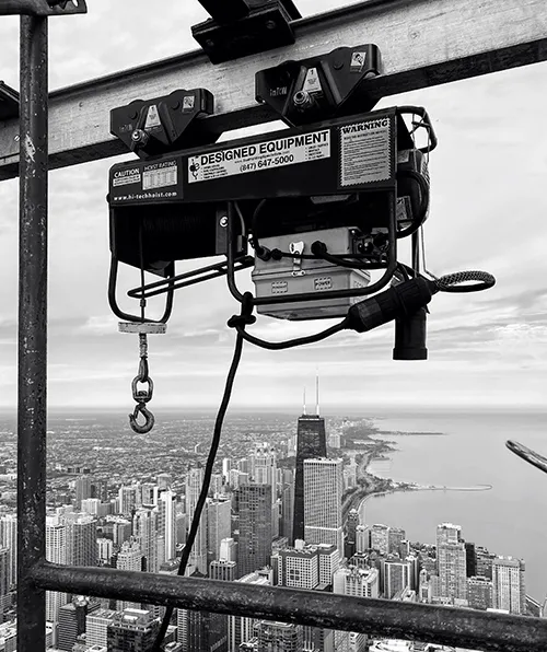 A Designed Equipment hoist hanging from a monorail beam high above downtown Chicago and the Lake Michigan shoreline